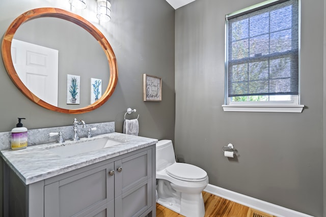 bathroom with plenty of natural light, wood-type flooring, toilet, and vanity