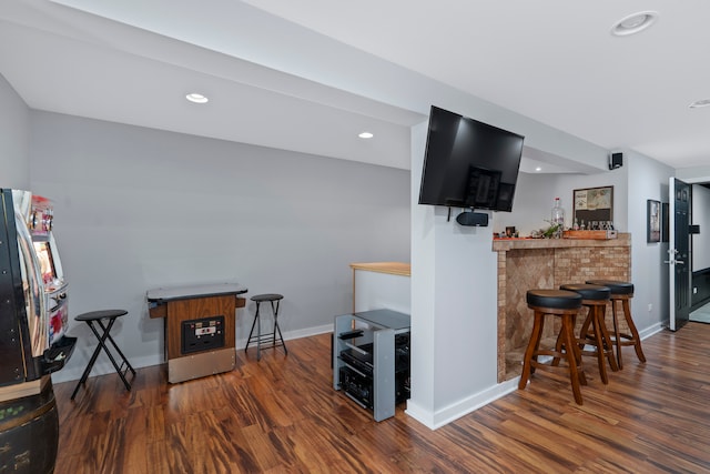 interior space with dark hardwood / wood-style flooring, kitchen peninsula, and a kitchen bar