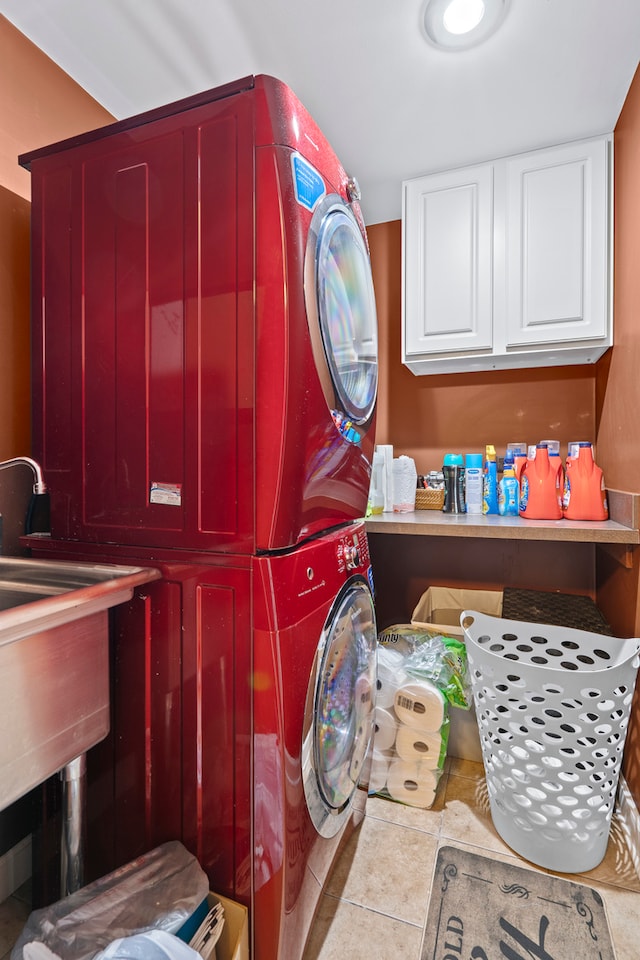 clothes washing area with cabinets, light tile patterned floors, and stacked washer / dryer