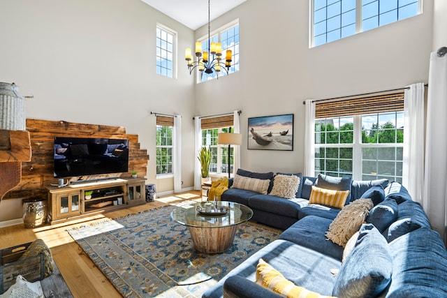 living room featuring an inviting chandelier, hardwood / wood-style flooring, and a towering ceiling