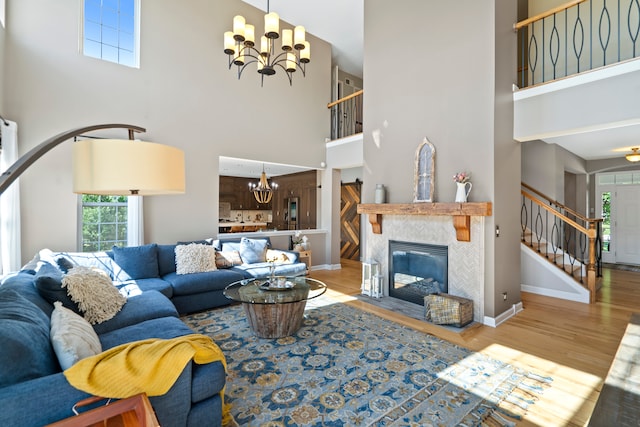 living room with a towering ceiling, a notable chandelier, hardwood / wood-style flooring, and a tile fireplace