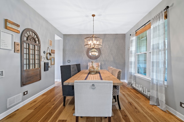 dining area with light hardwood / wood-style flooring, a chandelier, and plenty of natural light