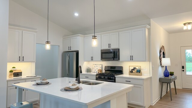 kitchen featuring white cabinets, vaulted ceiling, sink, and appliances with stainless steel finishes