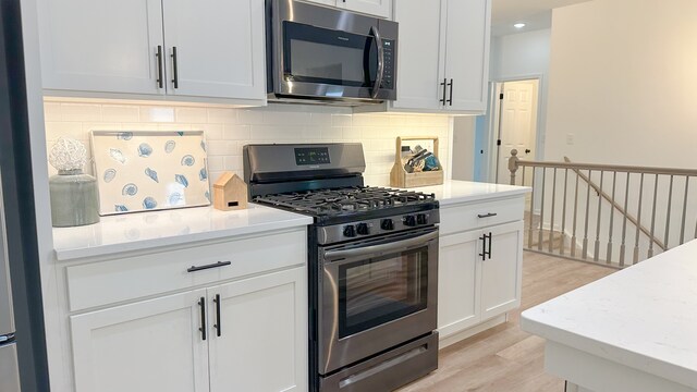 kitchen featuring light hardwood / wood-style floors, white cabinets, tasteful backsplash, light stone countertops, and appliances with stainless steel finishes