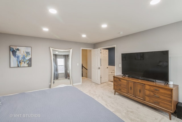 bedroom with ensuite bathroom and light carpet