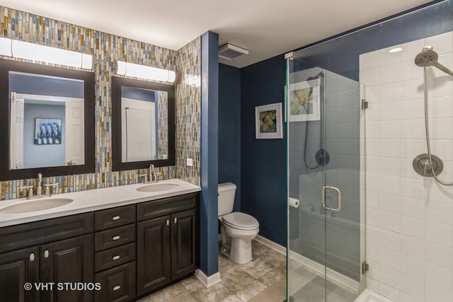 bathroom featuring a shower with door, vanity, and toilet