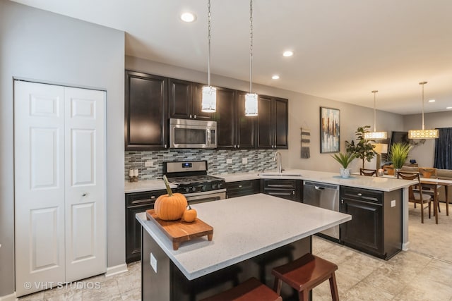 kitchen featuring sink, a center island, stainless steel appliances, decorative light fixtures, and a breakfast bar