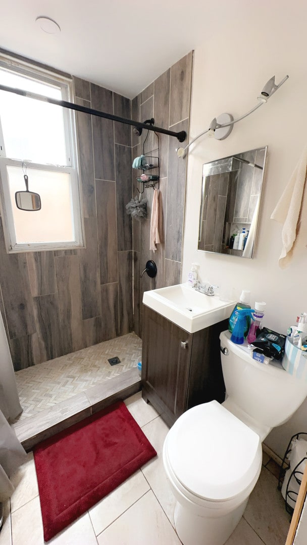 bathroom featuring toilet, vanity, tile patterned flooring, and tiled shower