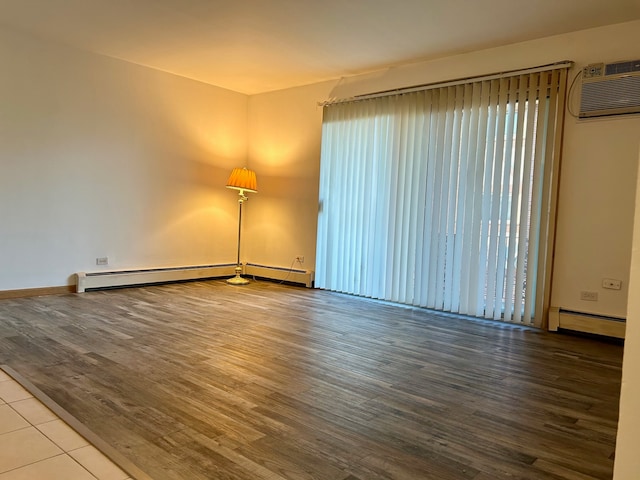 unfurnished room featuring a wall unit AC, hardwood / wood-style floors, and a baseboard radiator