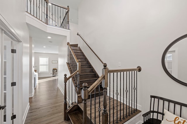 stairs with wood-type flooring and a high ceiling