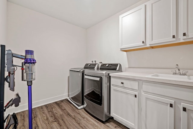 laundry room featuring cabinets, independent washer and dryer, light hardwood / wood-style floors, and sink