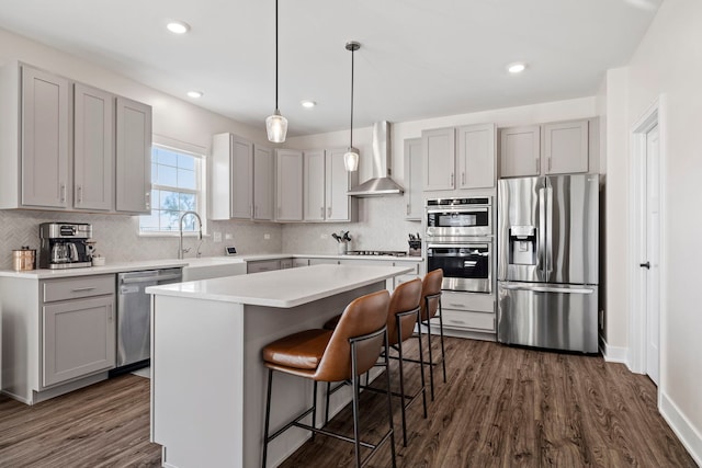 kitchen with a center island, wall chimney exhaust hood, stainless steel appliances, sink, and dark hardwood / wood-style floors