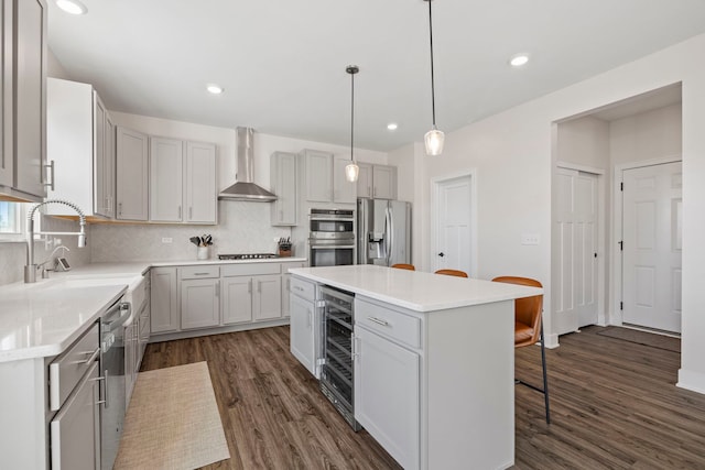 kitchen featuring pendant lighting, a center island, dark wood-type flooring, wall chimney range hood, and stainless steel appliances