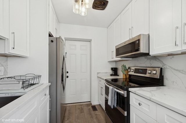 kitchen featuring appliances with stainless steel finishes, white cabinetry, dark wood-type flooring, and light stone counters