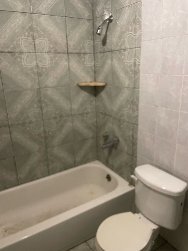 bathroom with tile walls, tiled shower / bath, and toilet