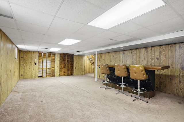 bar with wood walls, a paneled ceiling, and carpet