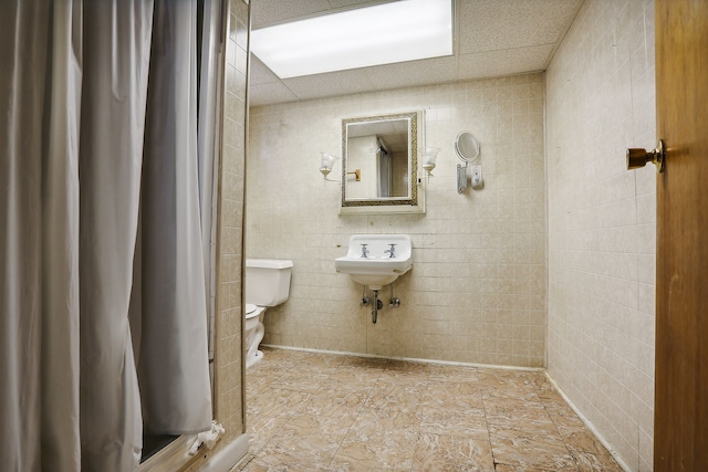 bathroom featuring toilet and tile walls