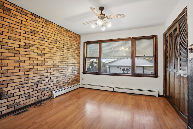 empty room with light hardwood / wood-style floors, ceiling fan, a baseboard radiator, and brick wall