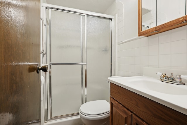 bathroom with vanity, toilet, backsplash, and a shower with shower door