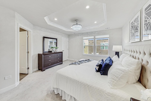 bedroom with a raised ceiling, ceiling fan, and light colored carpet