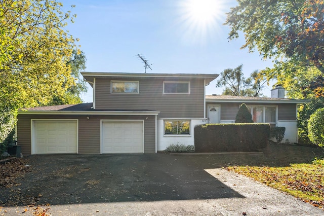 view of front of home with driveway, a chimney, and a garage