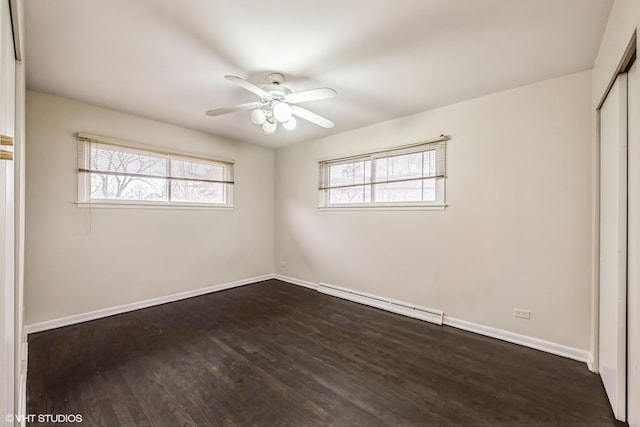 empty room featuring ceiling fan, dark wood-type flooring, and a baseboard heating unit