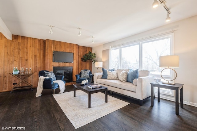 living room with wood finished floors, track lighting, and wood walls