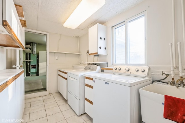 clothes washing area with sink, cabinets, washer and dryer, and light tile patterned floors