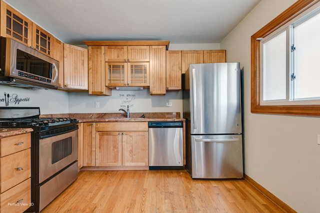 kitchen featuring sink, light wood-type flooring, light brown cabinetry, stone countertops, and stainless steel appliances