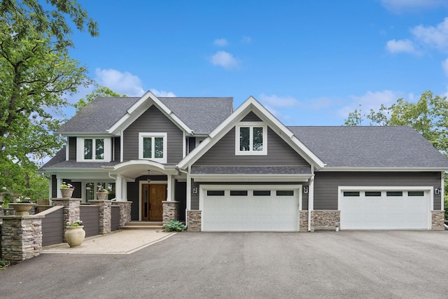 craftsman inspired home with aphalt driveway, stone siding, and a garage