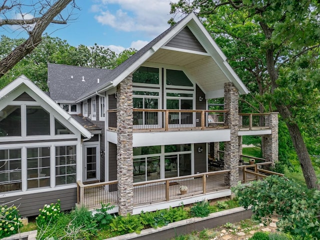 rear view of house with a balcony and roof with shingles