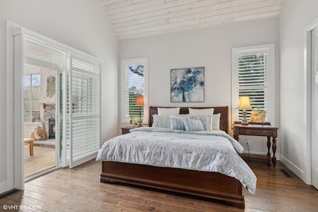 bedroom featuring access to exterior, multiple windows, wood finished floors, and vaulted ceiling