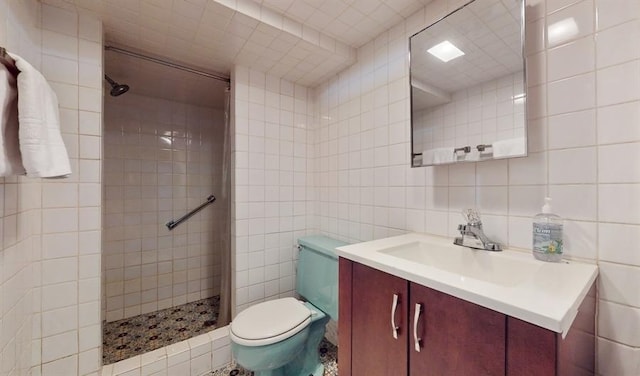 bathroom featuring vanity, toilet, tile walls, and a tile shower