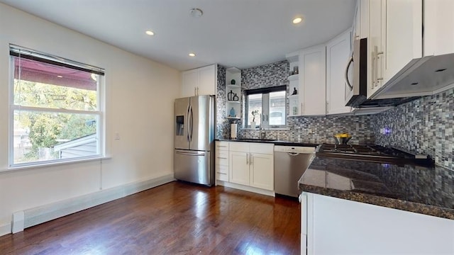 kitchen with plenty of natural light, stainless steel appliances, dark stone counters, and white cabinets