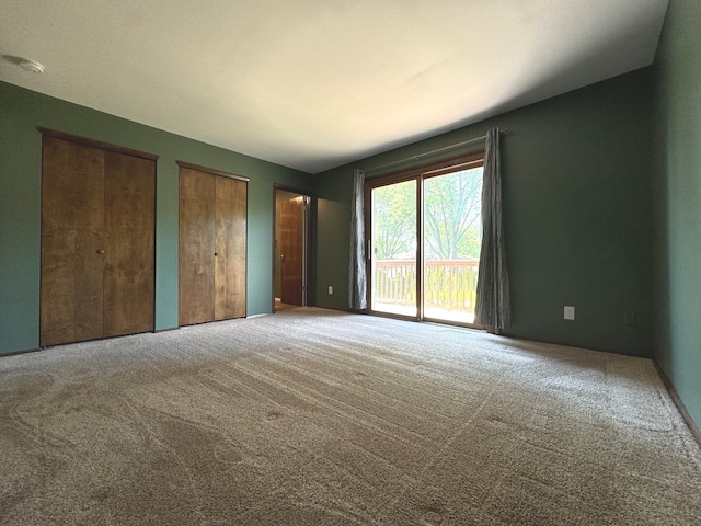 interior space featuring access to outside, carpet, and two closets