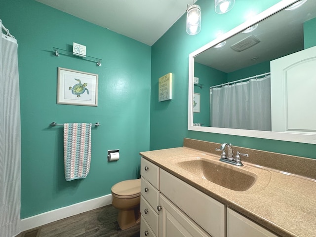 bathroom with toilet, vanity, and wood-type flooring