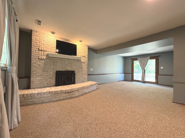 unfurnished living room featuring carpet flooring and a wood stove