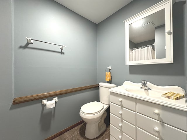 bathroom with toilet, vanity, and tile patterned floors