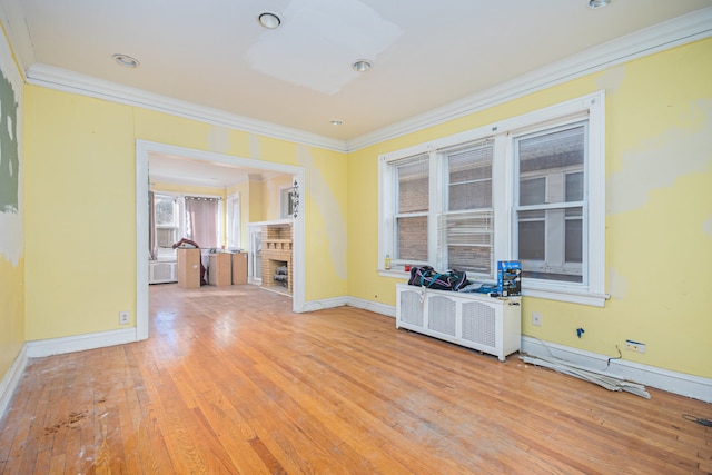 empty room with light hardwood / wood-style floors, radiator, and ornamental molding