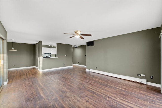 unfurnished living room featuring baseboard heating, ceiling fan, and dark wood-type flooring