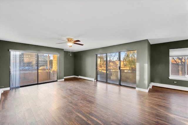 empty room featuring dark hardwood / wood-style flooring, baseboard heating, and ceiling fan