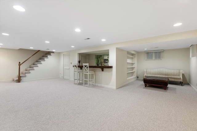 interior space with bar, built in shelves, and light colored carpet