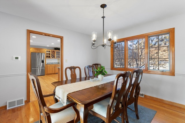 dining area with light hardwood / wood-style floors and a chandelier