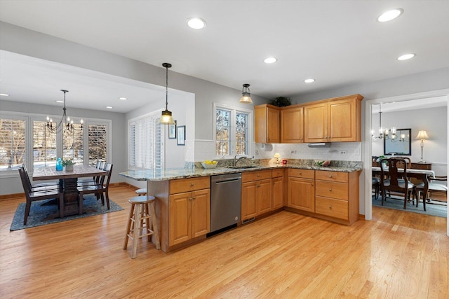 kitchen featuring dishwasher, a kitchen bar, a chandelier, light hardwood / wood-style floors, and kitchen peninsula