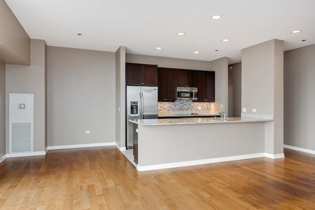 kitchen with appliances with stainless steel finishes, backsplash, visible vents, and light wood-style floors