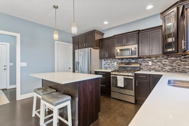 kitchen with decorative backsplash, appliances with stainless steel finishes, dark brown cabinetry, and pendant lighting