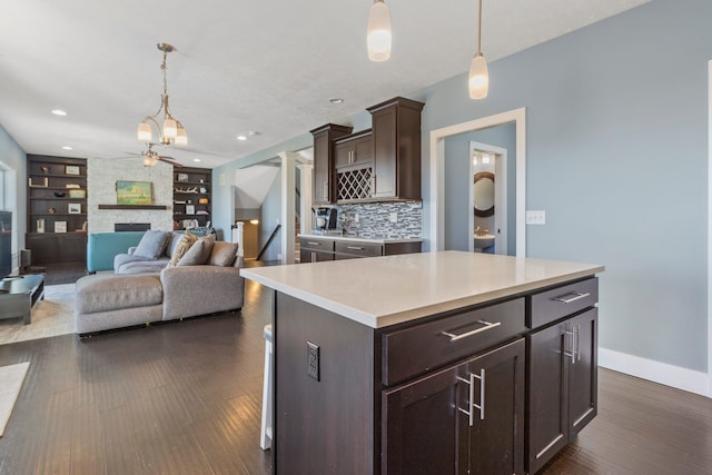 kitchen with pendant lighting, a kitchen island, a stone fireplace, and built in features