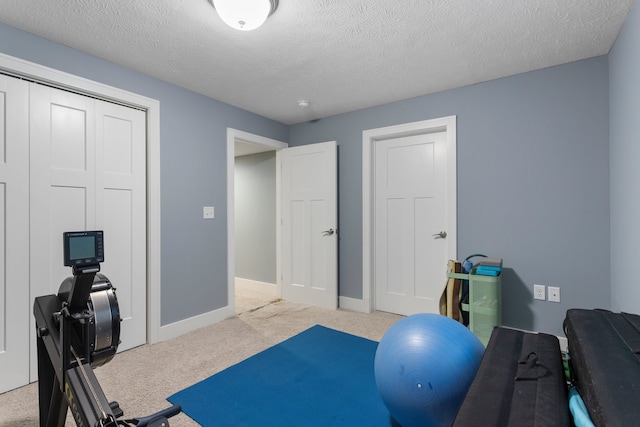 exercise room featuring light carpet and a textured ceiling