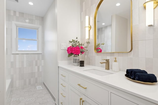 bathroom with vanity, tile walls, backsplash, and a tile shower