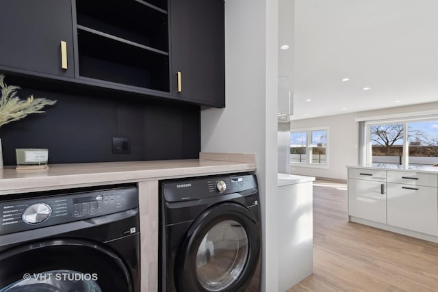 laundry area featuring cabinets, separate washer and dryer, and light wood-type flooring